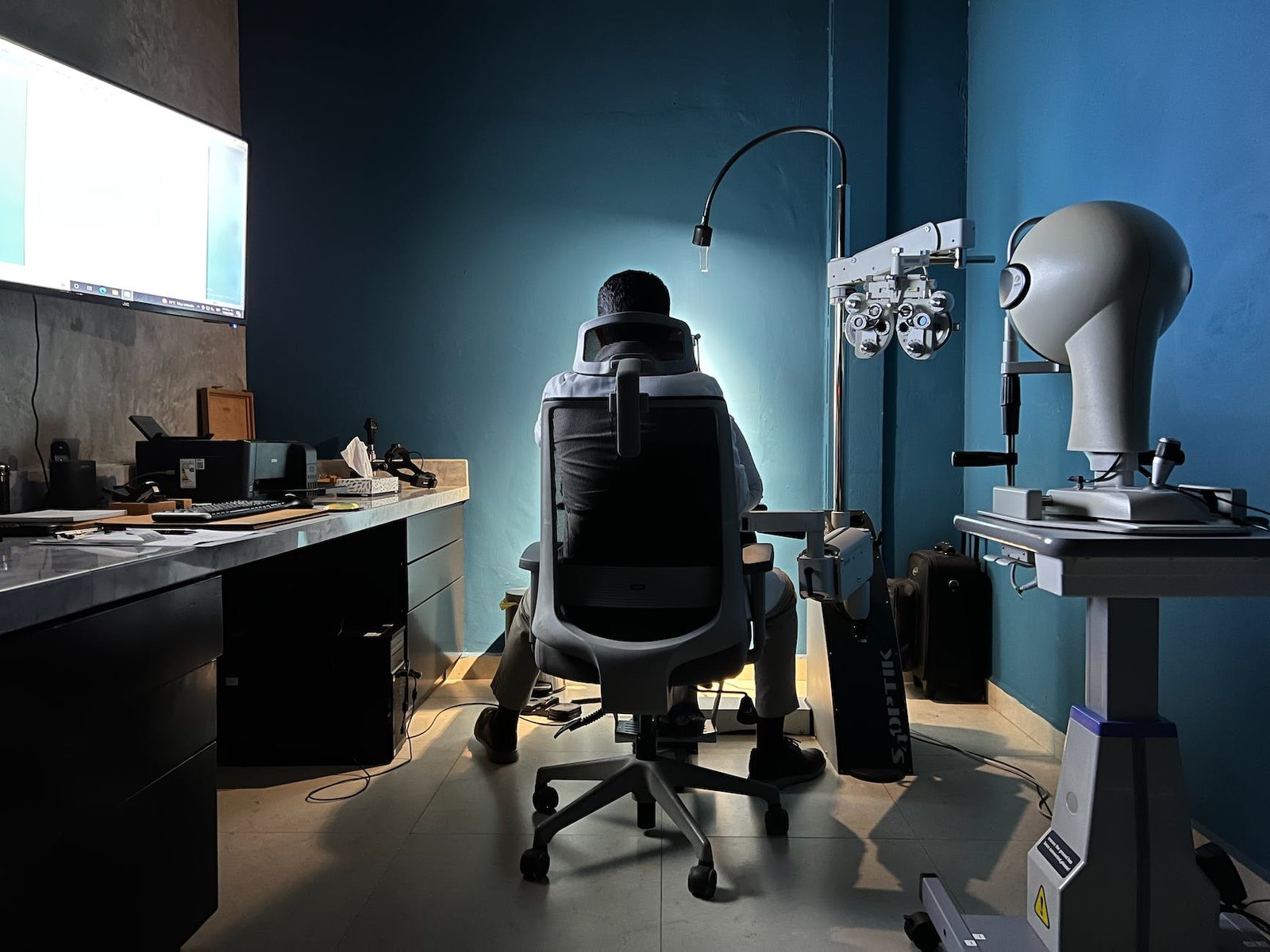 back view of an eye care professional sitting on a chair in the examination room
